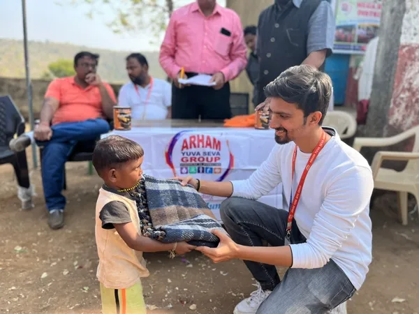 AYSG volunteer distributing blankets to a child